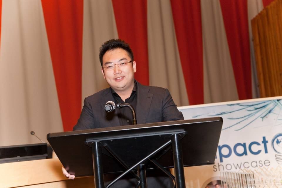Kevin Xu smiling at a podium