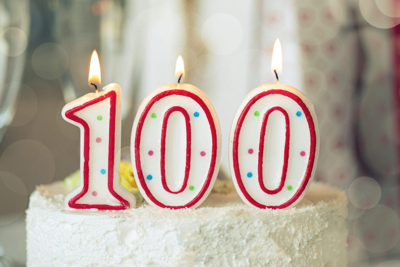 Birthday cake with candles that are lit and spell out 100