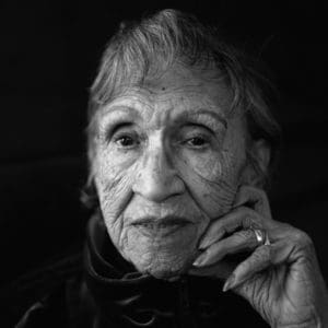 Black and white photo of older woman with her hand on her face and a ring on her finger