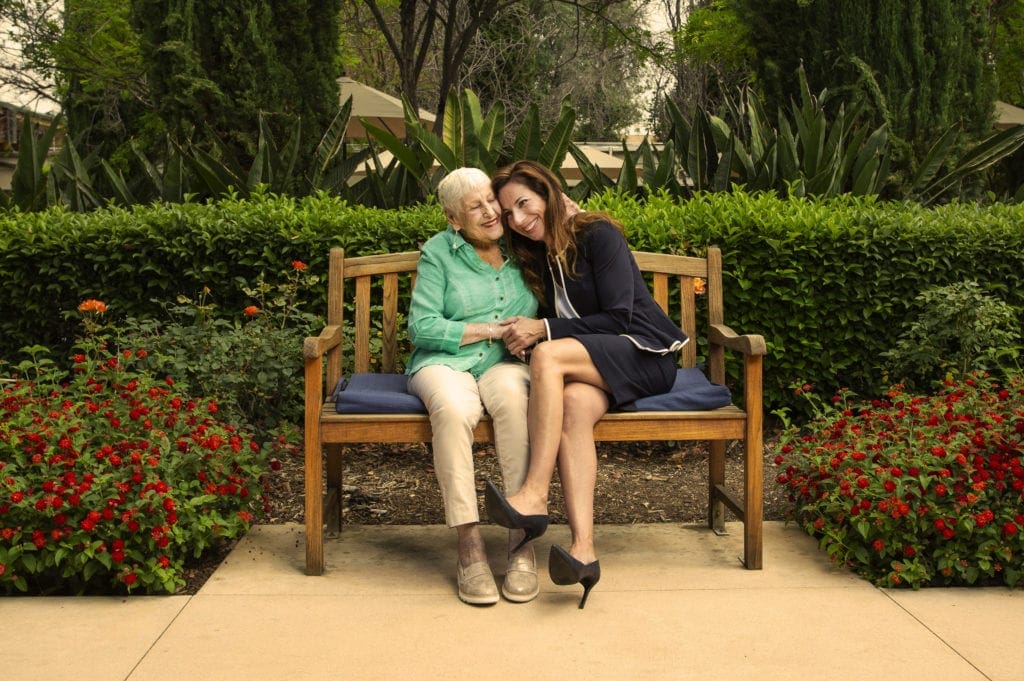 Resident Lorraine Beckenstein and Larissa Stepanians MS '01 embrace on a bench in a courtyard of the LA Jewish Home