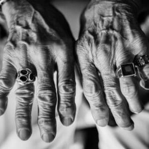 Black and white photograph of a pair of an older person's hands wearing three rings