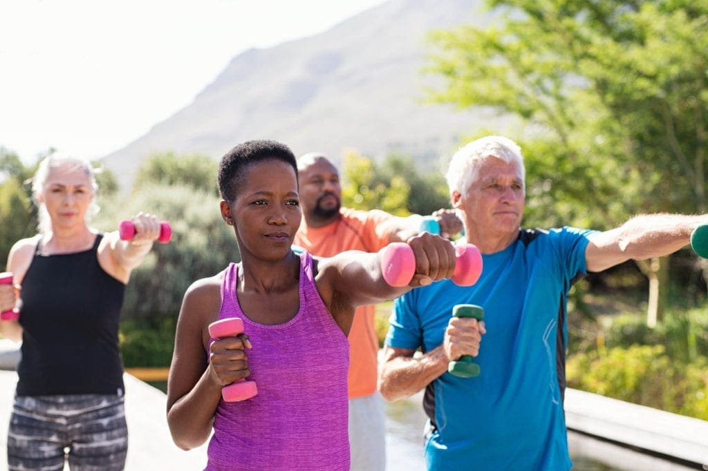 Older people exercising outdoors with dumbbells