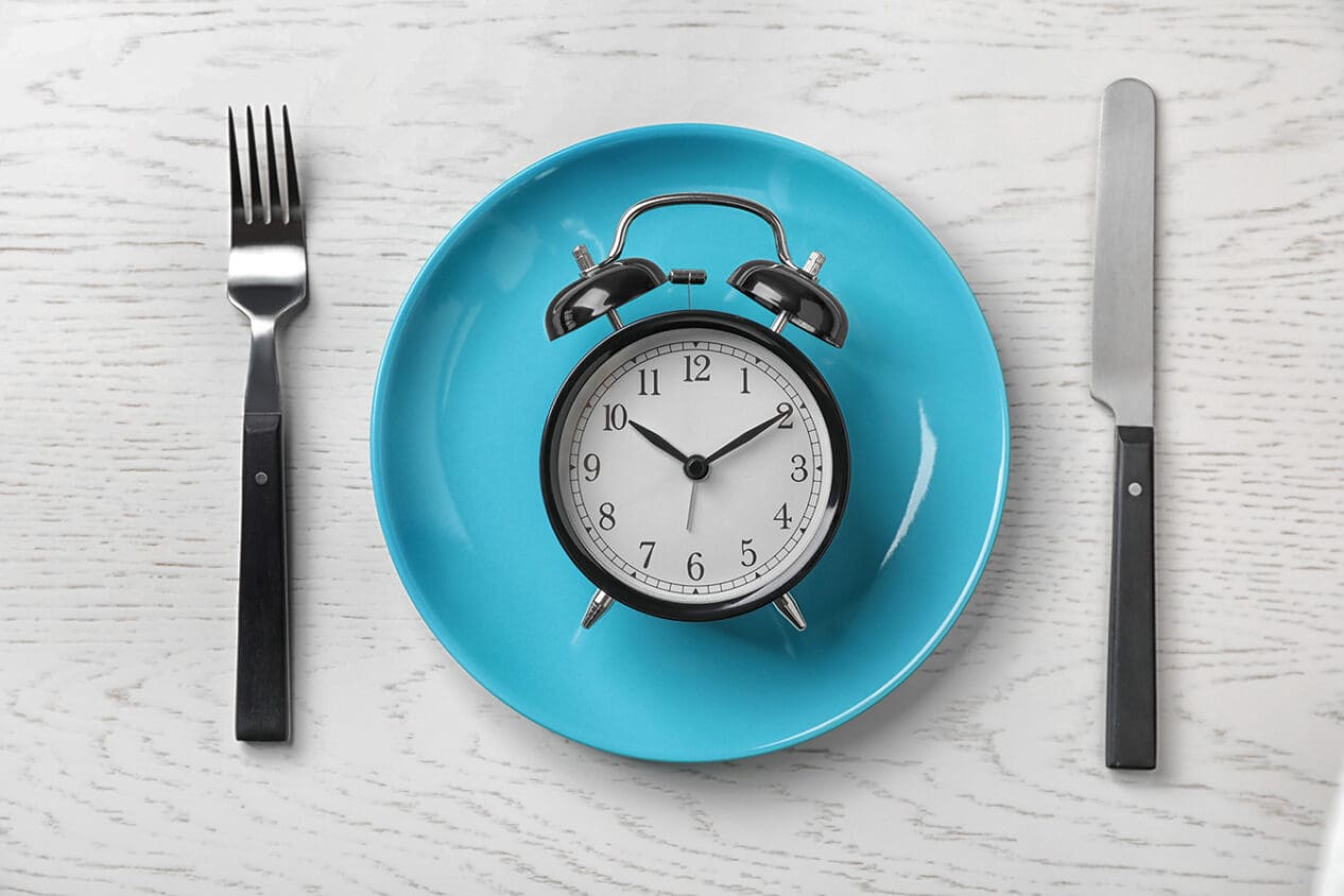 Clock on empty plate with fork and knife