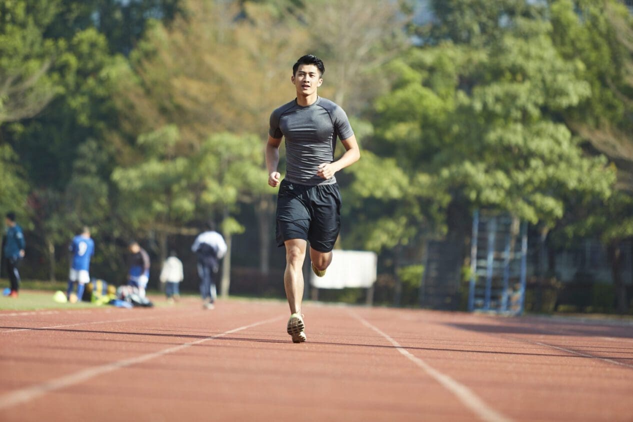 Young man running on track field
