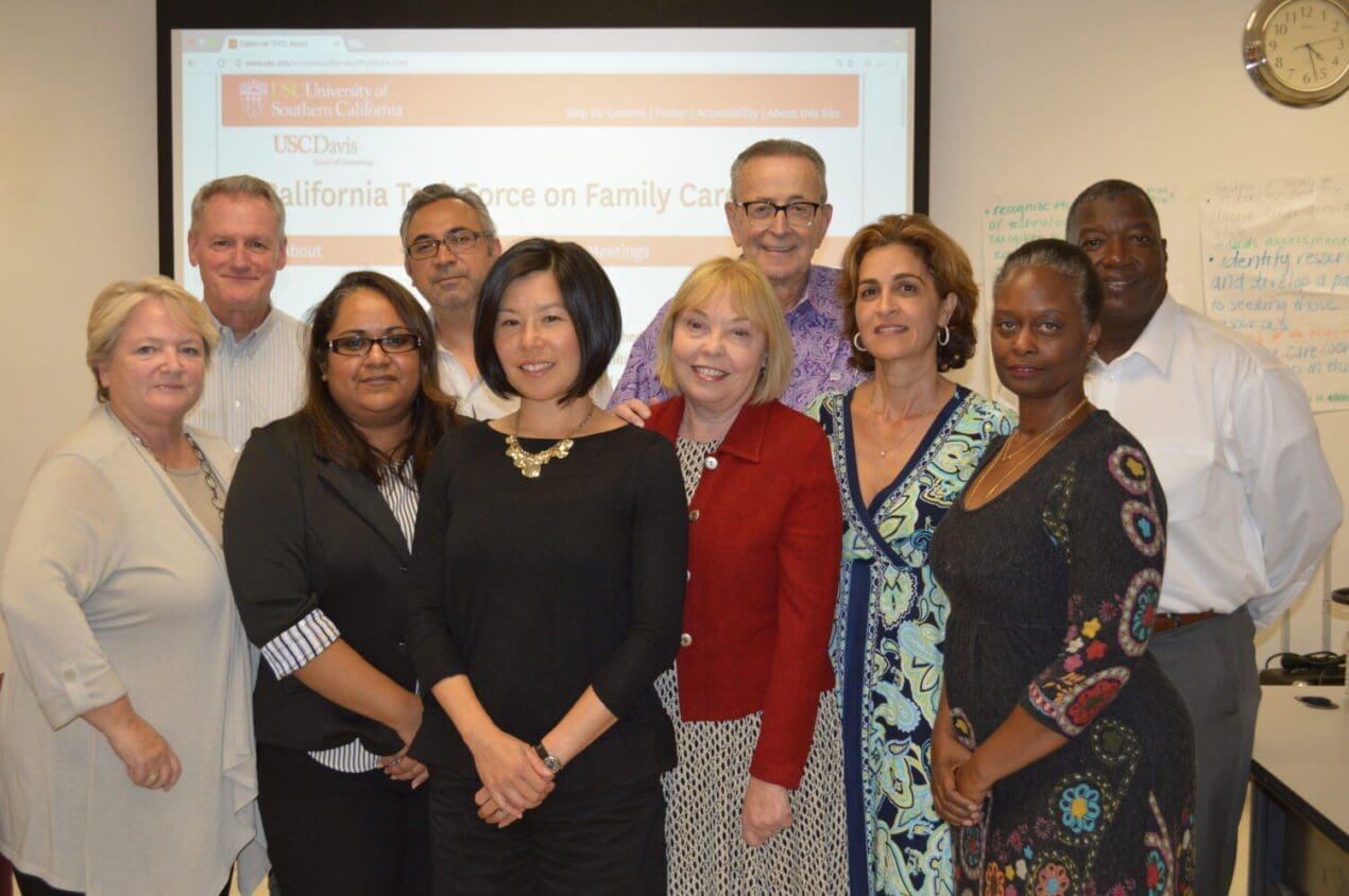 Group of individuals standing together in front of a screen for the California Task Force on Family Caregiving