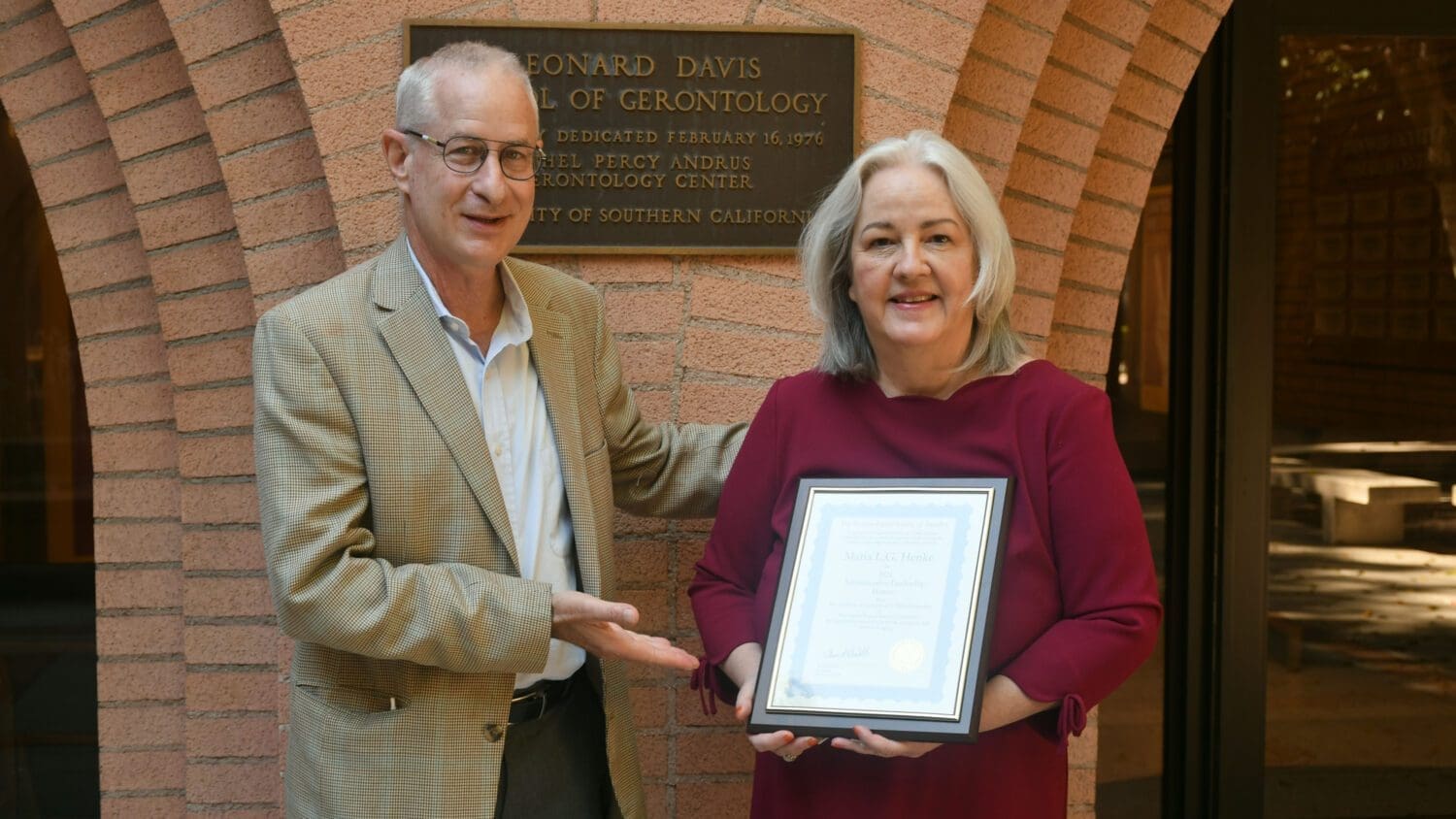 Dean Pinchas Cohen next to Senior Associate Dean Maria Henke holding a frame