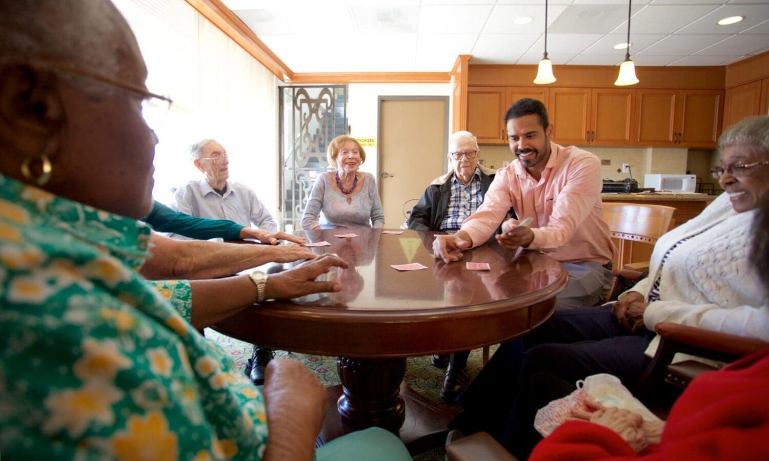 Younger person enjoying a card game with group of older people