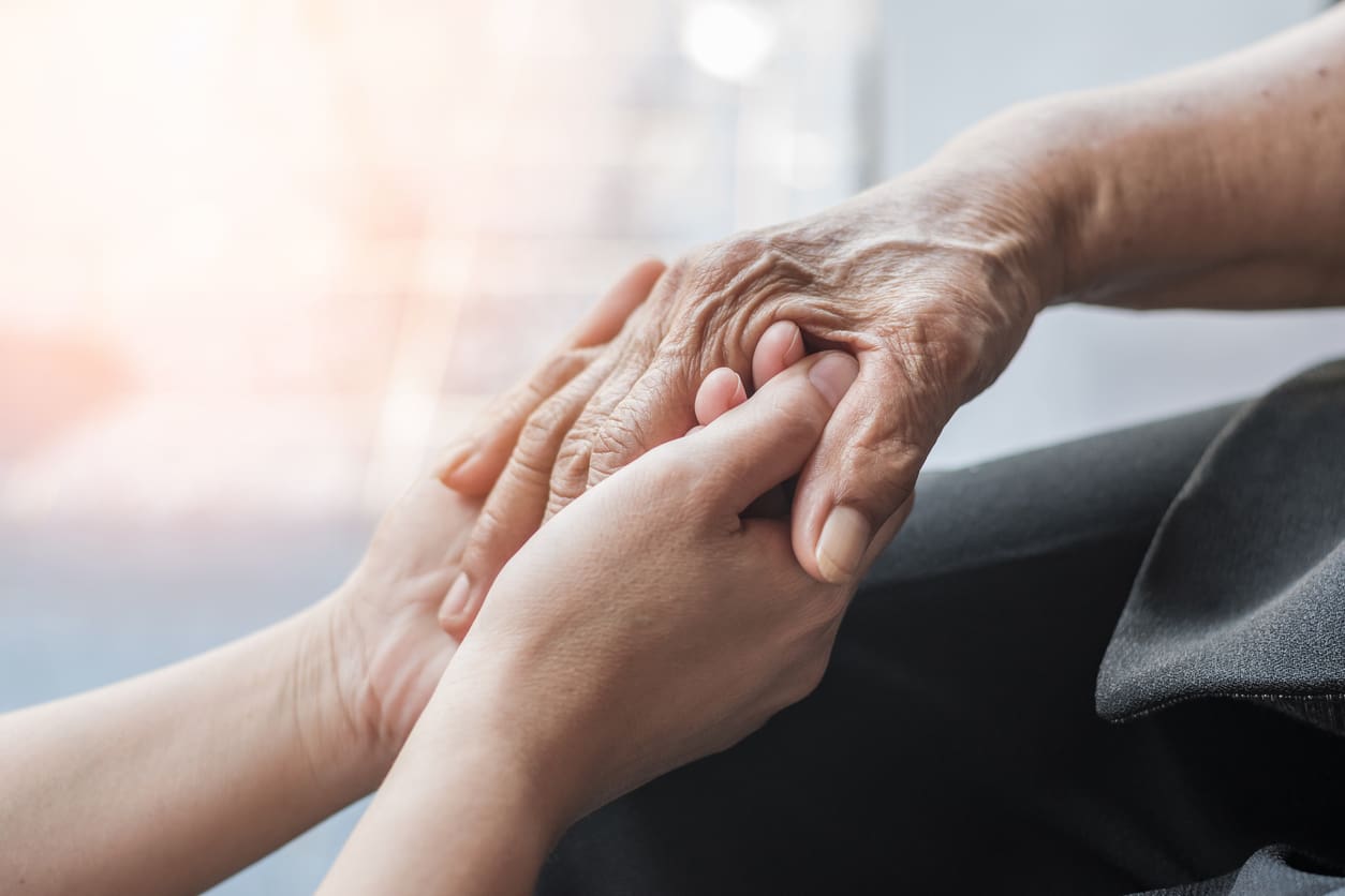 A pair of young hands holding an older person's hand