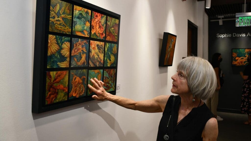 Artist touching her gallery piece, which consists of many frames showing her art