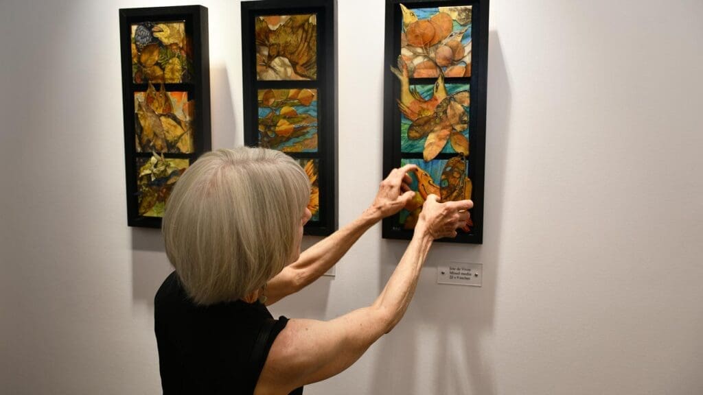 Woman touching her artwork that is hung up