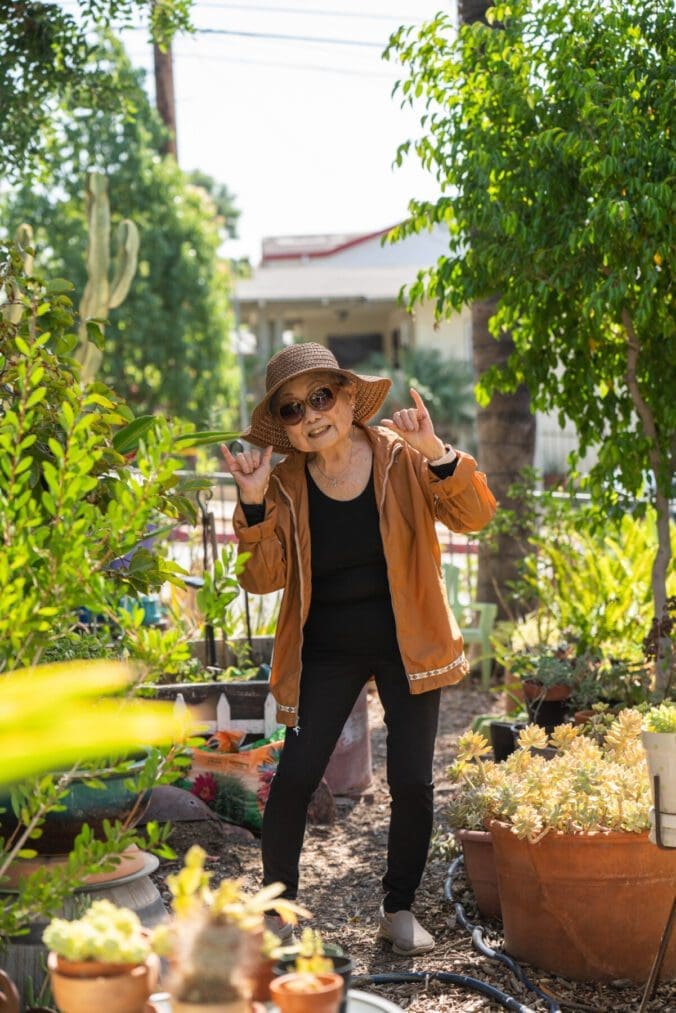 Frances Ito in her garden making the shaka hand gesture