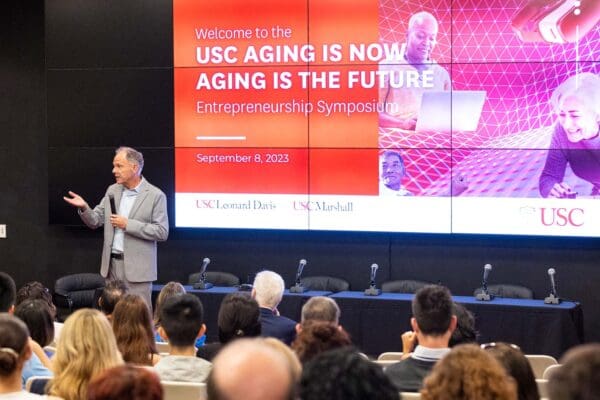Dr. Geoffrey Garrett, Dean of USC Marshall School of Business presenting the Symposium on Future of Aging