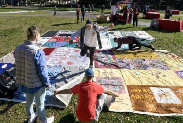 Workers and volunteers assemble sections of the AIDS Quilt out on McCarthy quad during AIDS quilt memorial and life celebration for World AIDS Day