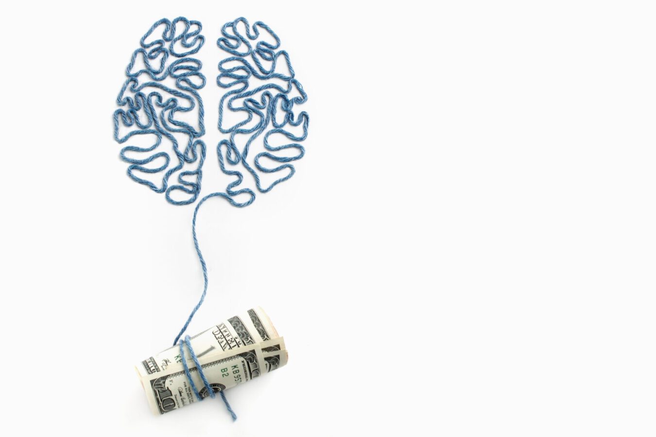 Brain and money connected by a thread on a white background